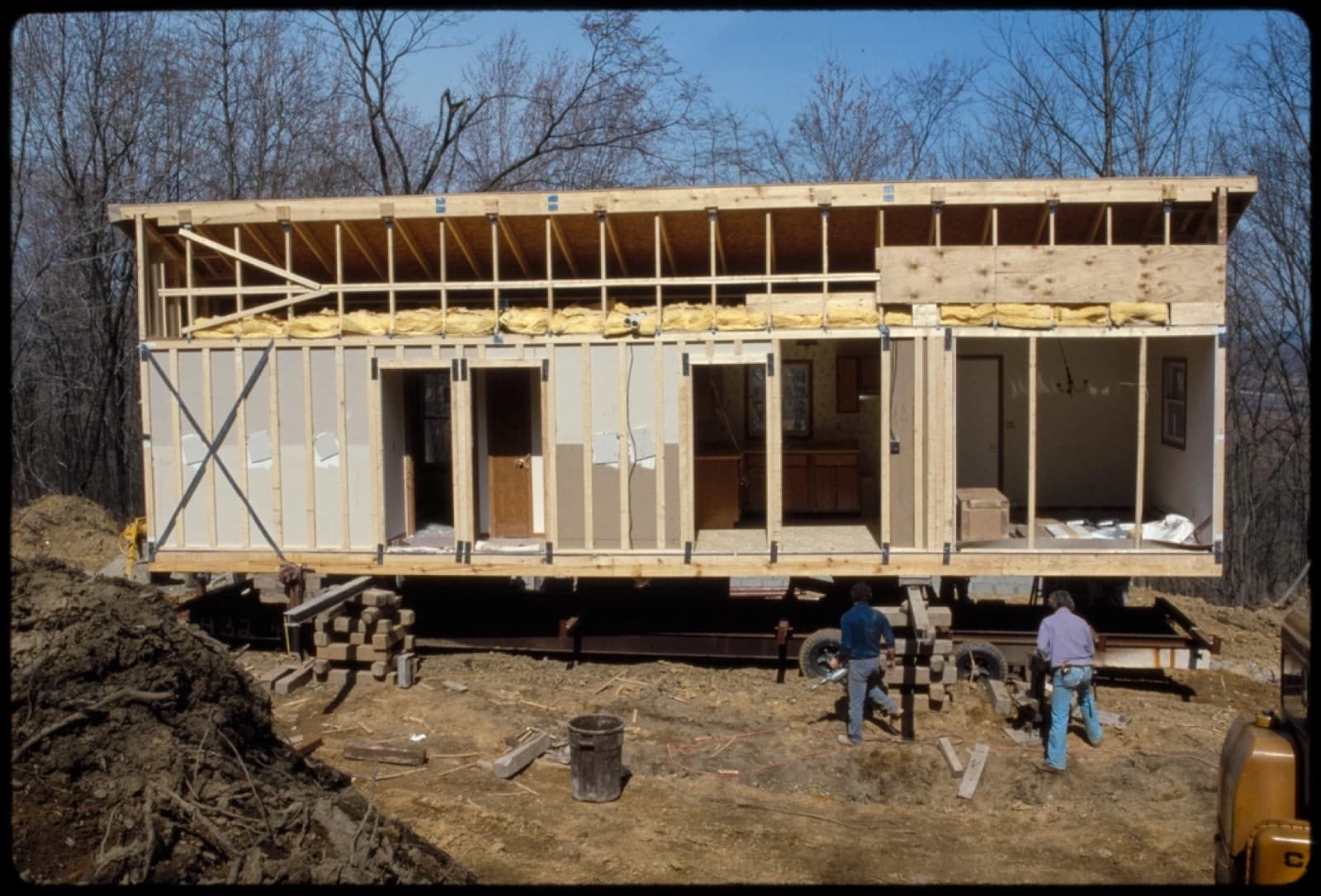 Crews assembling a modular house section on a prepared site