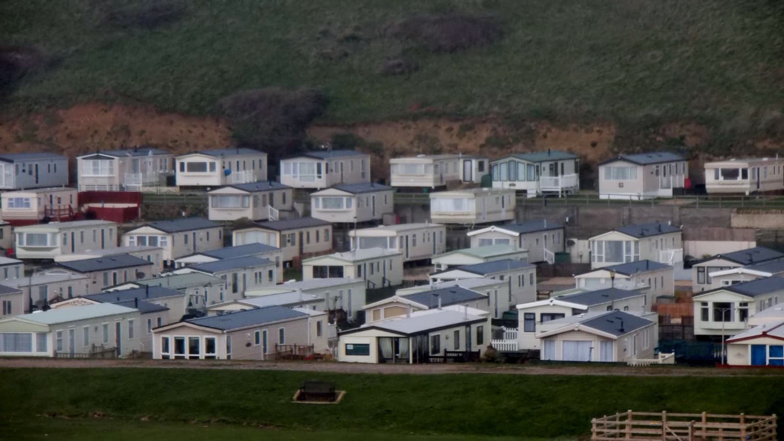 Rows of manufactured homes lined up on a hillside lot