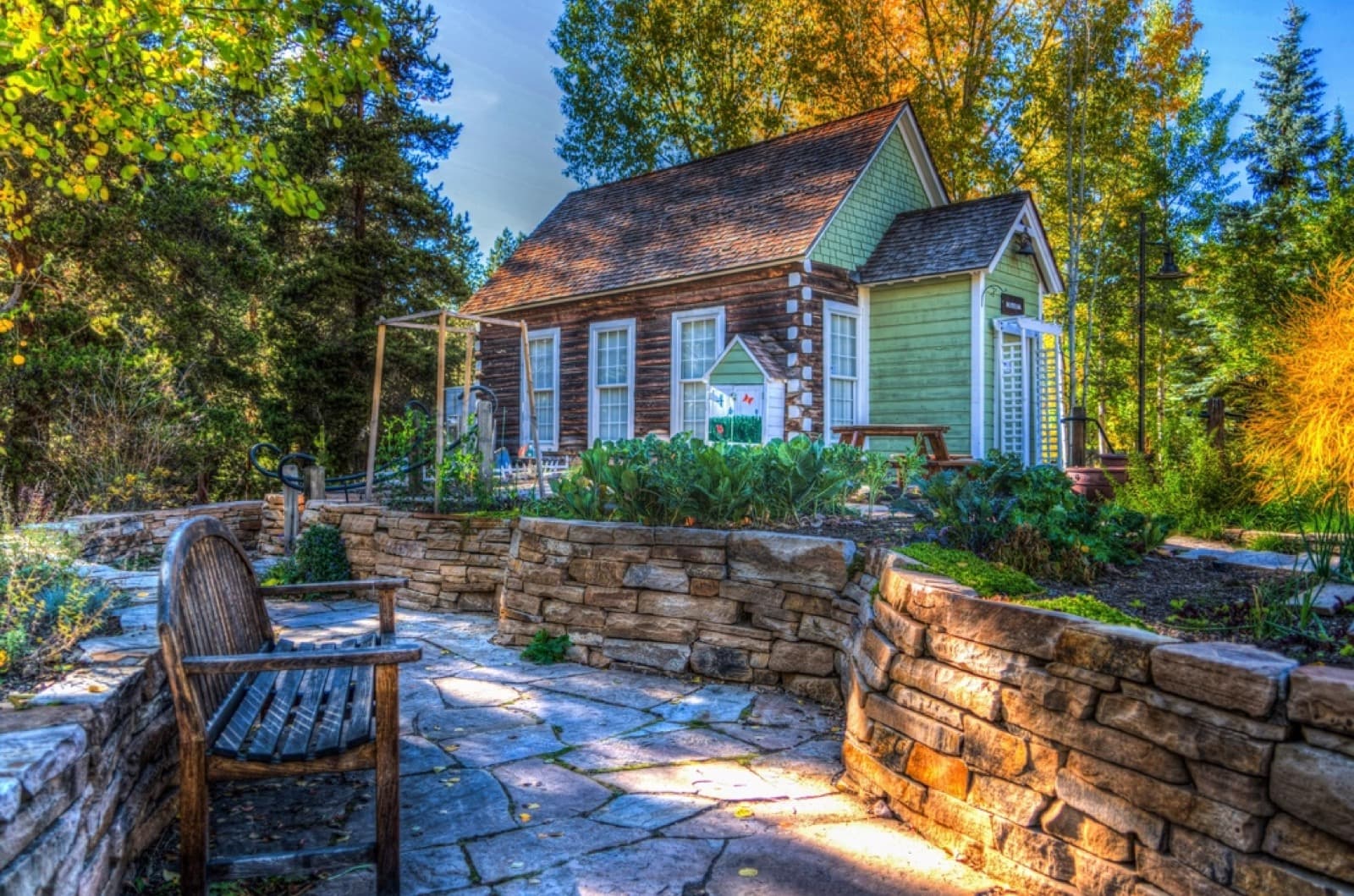 A tiny house surrounded by trees and a stone retaining wall